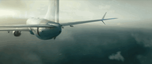 A Plane Is Flying Through A Cloudy Sky With A Blue Tail GIF