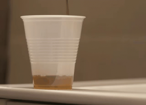 A Plastic Cup Filled With Brown Liquid Sits On A Counter GIF