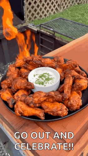 A Plate Of Chicken Wings With A Dipping Sauce And Fire Coming Out Of Them . GIF