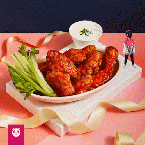 A Plate Of Chicken Wings With Celery On A Pink Table GIF