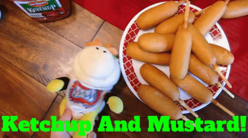 A Plate Of Corn Dogs Next To A Bottle Of Ketchup And Mustard GIF