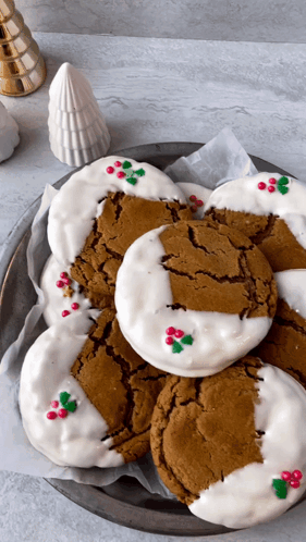 A Plate Of Gingerbread Cookies With White Frosting And Holly On Them GIF