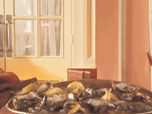 A Plate Of Oysters Sits On A Table In Front Of A Pink Wall GIF