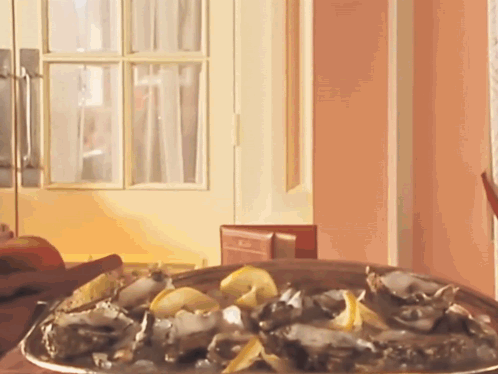 A Plate Of Oysters Sits On A Table In Front Of A Pink Wall GIF