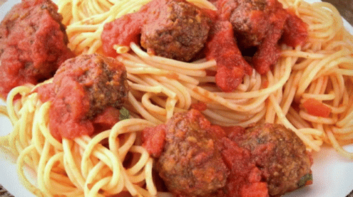 A Plate Of Spaghetti And Meatballs Covered In Sauce GIF