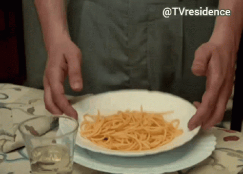 A Plate Of Spaghetti Is On A Table With A Glass Of Wine GIF