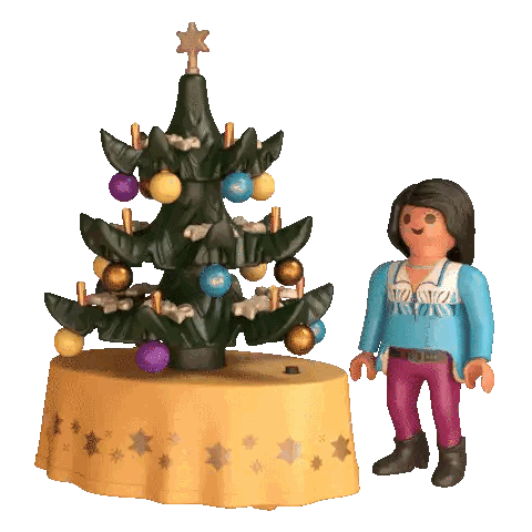 a playmobil figurine stands next to a christmas tree