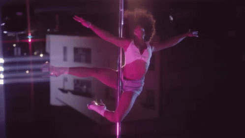A Pole Dancer In A Pink Outfit Is Dancing In The Dark GIF