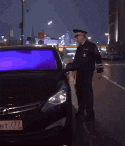 A Police Officer Checks A Car 'S Rear View Mirror GIF