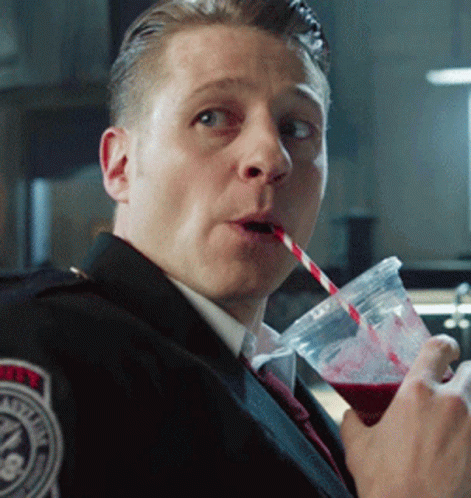 A Police Officer Drinks Through A Straw From A Cup With A Badge On His Shoulder GIF