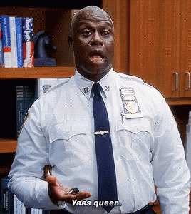 A Police Officer In A White Shirt And Blue Tie Is Holding Something In His Hand And Saying Yaas Queen GIF