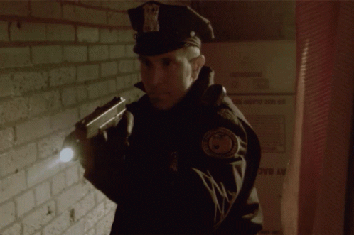 Police Officer Holding Gun In Front Of Wall GIF