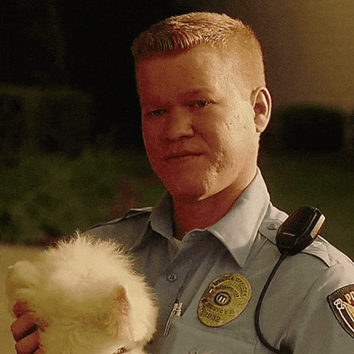 A Police Officer Is Holding A Small White Dog In His Arms GIF
