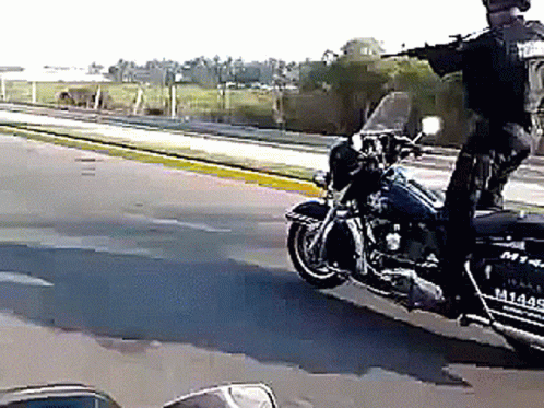 A Police Officer Is Riding A Harley Davidson Motorcycle On The Street GIF