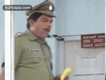 A Police Officer Is Standing In Front Of A Door Holding A Yellow Object . GIF