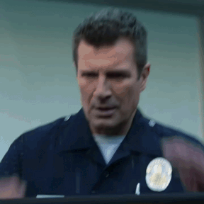 A Police Officer Is Standing In Front Of A Window And Looking Out . GIF