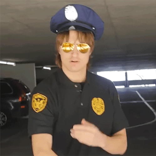 A Police Officer Wearing Sunglasses And A Hat Has A Badge On His Shoulder GIF