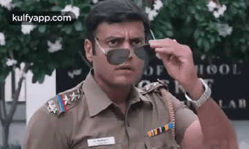 A Police Officer Wearing Sunglasses Is Making A Funny Face . GIF