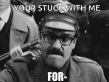 A Police Officer With Glasses And A Mustache Is Holding A Gun In A Black And White Photo . GIF