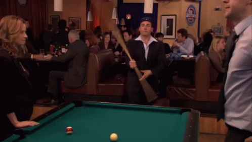 A Pool Table In A Bar With A Sign That Says Budweiser GIF