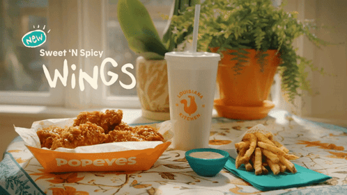 A Popeye 'S Advertisement Shows A Tray Of Chicken Wings And French Fries GIF