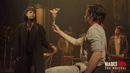 A Poster For Hadestown The Musical Shows A Man Holding A Woman 'S Hand GIF