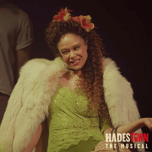 A Poster For Hadestown The Musical Shows A Woman In A Green Dress And Fur Coat GIF