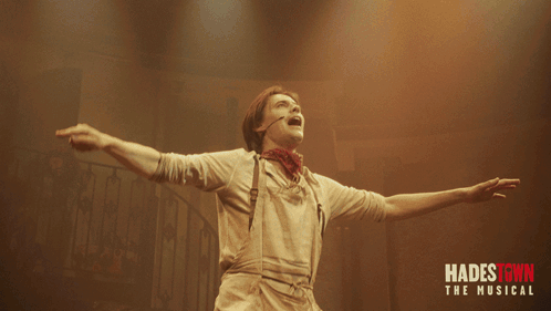 A Poster For Hadestown The Musical With A Man Holding A Red Flower GIF