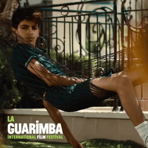 A Poster For La Guarimba International Film Festival With A Man Laying In A Hammock GIF