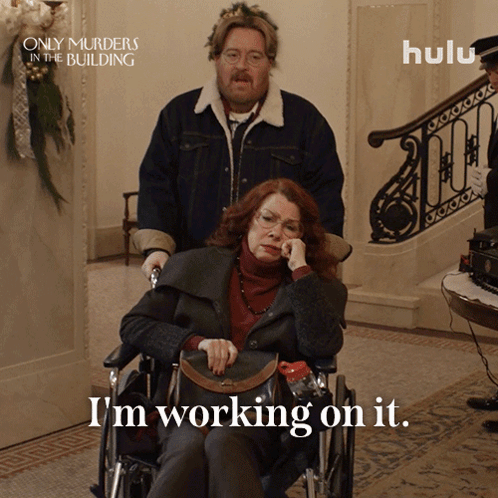 A Poster For Only Murders In The Building Shows A Woman In A Wheelchair And Says I 'M Working On It GIF