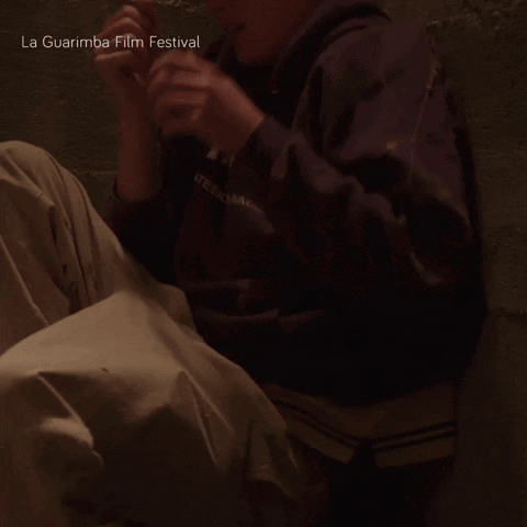 A Poster For The La Guarimba Film Festival With A Person Sitting On The Floor GIF