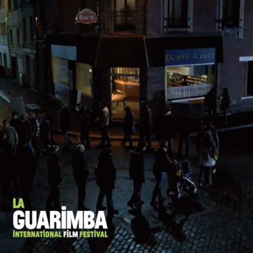 A Poster For The La Guarimba International Film Festival Shows A Group Of People Walking Down A Cobblestone Street GIF