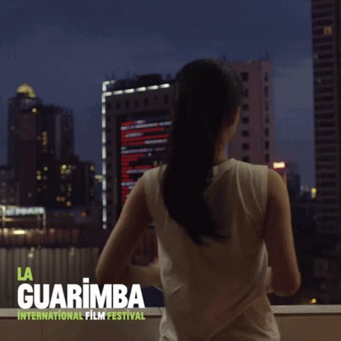 A Poster For The La Guarimba International Film Festival Shows A Woman Looking Out A Window GIF