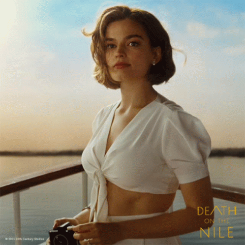 A Poster For The Movie Death On The Nile Shows A Woman In A White Top GIF