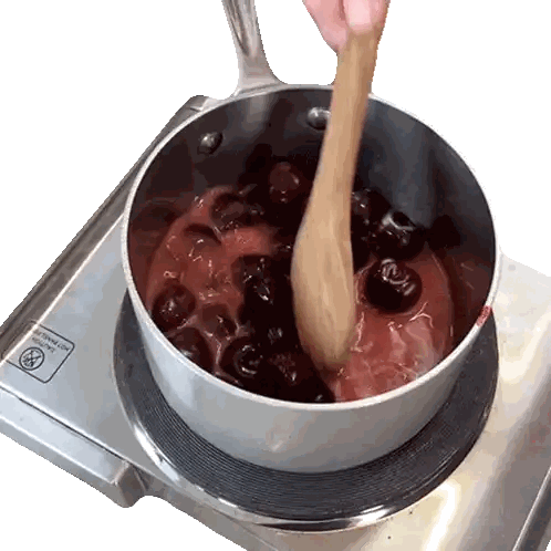 a pot of cherries is being stirred on a stove top