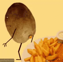 A Potato With Arms And Legs Is Standing Next To A Plate Of French Fries .. GIF