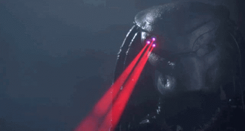 A Predator 'S Eyes Are Glowing Red In The Dark GIF
