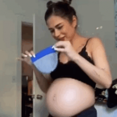 A Pregnant Woman In A Black Top Is Holding A Blue Bowl . GIF