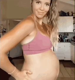 a pregnant woman in a pink bra is holding her belly .