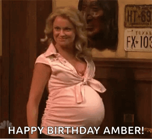 A Pregnant Woman With A Big Belly Is Standing In Front Of A Wall And Says `` Happy Birthday Amber '' . GIF