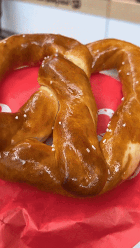 A Pretzel Is Sitting On A Red Napkin With A White S On It GIF