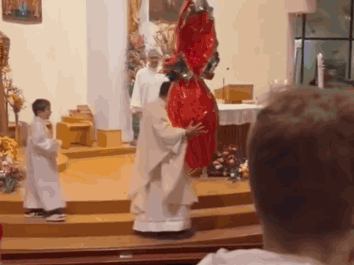 A Priest Holds A Large Red Easter Egg In His Hands GIF
