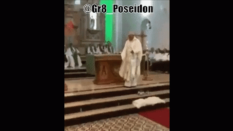 A Priest In A White Robe Is Standing On A Stage In A Church GIF