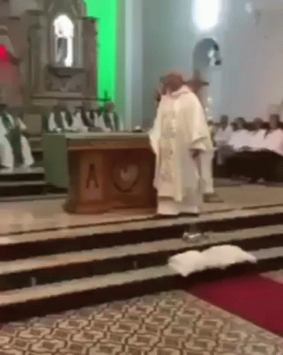 A Priest In A White Robe Stands In Front Of An Altar With A Heart On It GIF