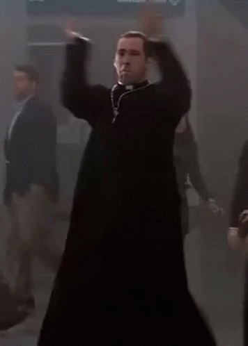 A Priest Is Dancing In A Dark Room With A Group Of People Behind Him . GIF