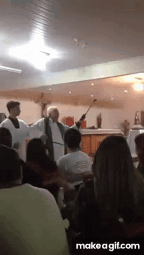 A Priest Is Giving A Sermon In Front Of A Crowd Of People GIF