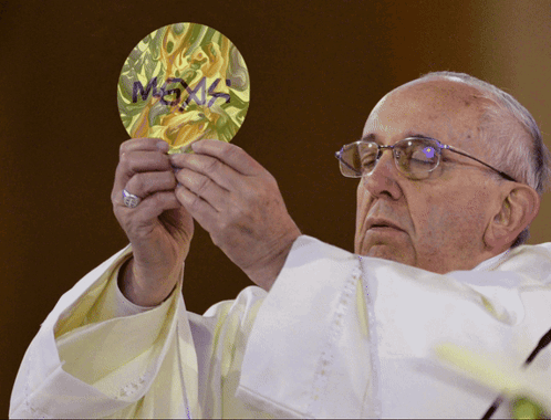 A Priest Is Holding A Piece Of Paper That Says ' Megas ' On It GIF