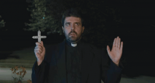 A Priest Is Holding A Small Cross In His Hands GIF