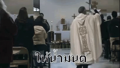 A Priest Is Standing In Front Of A Crowd Of People In A Church Giving A Sermon . GIF