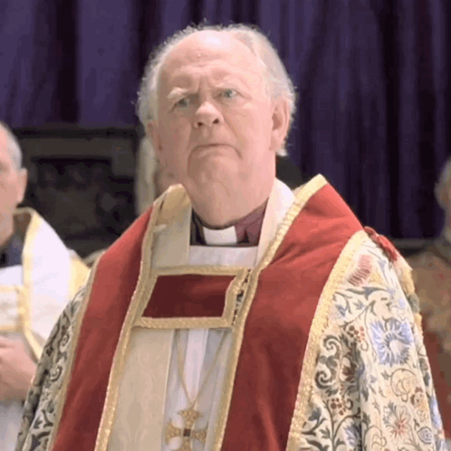 A Priest Wearing A Red And Gold Robe Stands In Front Of A Purple Background GIF